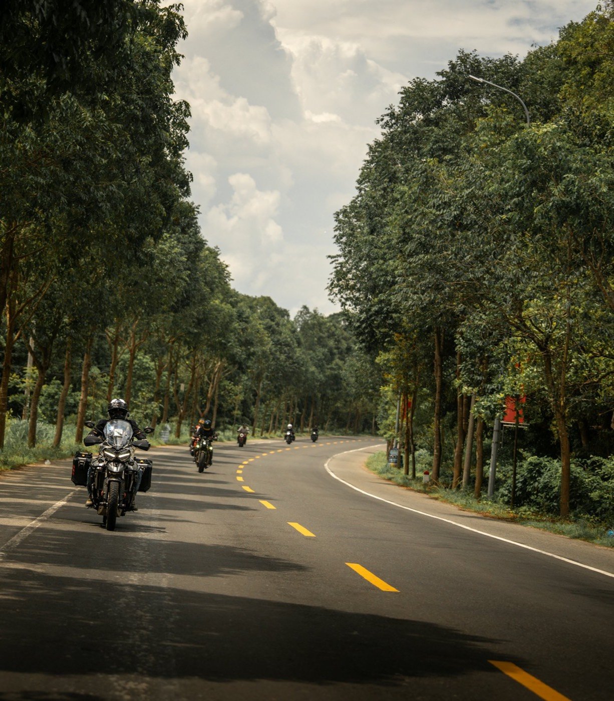 Riders on loaded adventure motorcycles moving together along a road