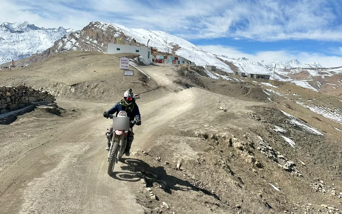 A rider on an adventure bike on a dirt track high in Spiti, far from any network