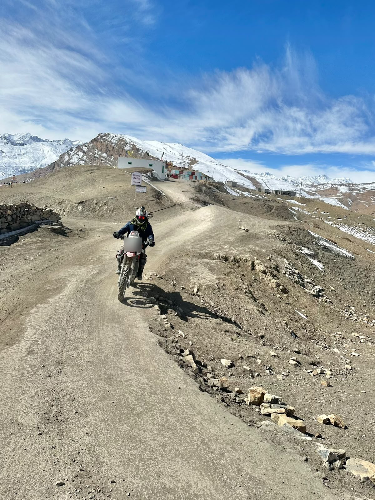 A rider on an adventure bike on a dirt track high in Spiti, far from any network