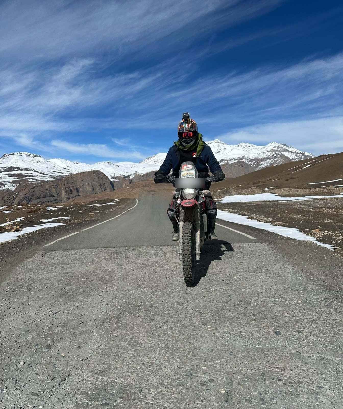 A rider on an adventure bike riding straight down an empty high-altitude road